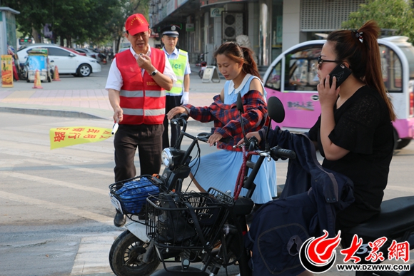 文明交通劝导员正在协助交警执勤